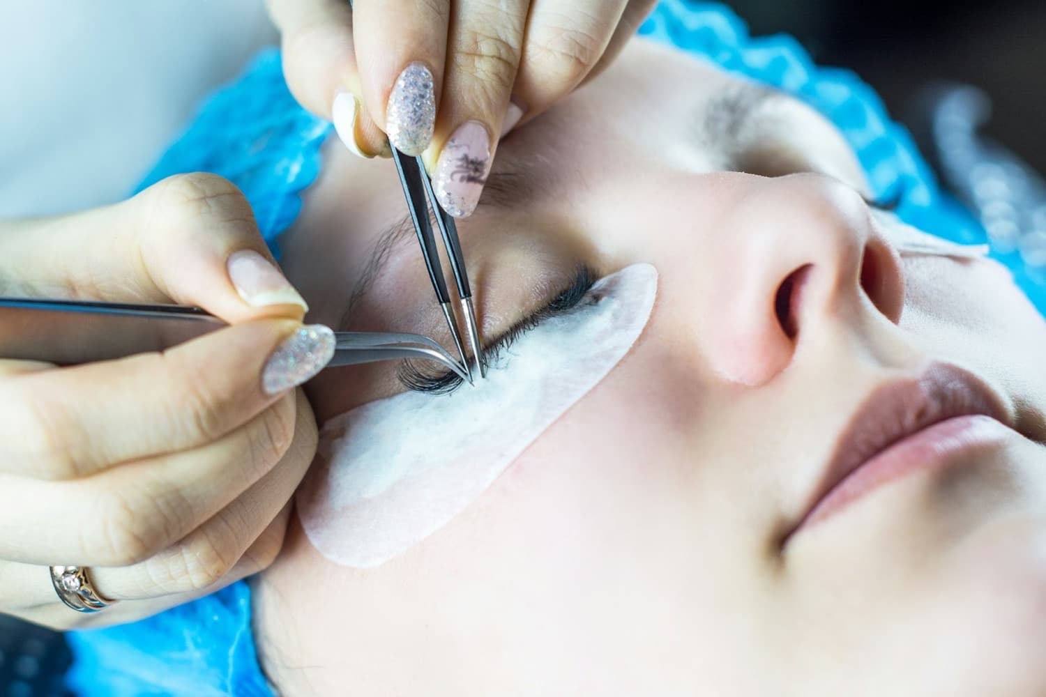 Two pairs of tweezers isolating a lash during an extension appointment
